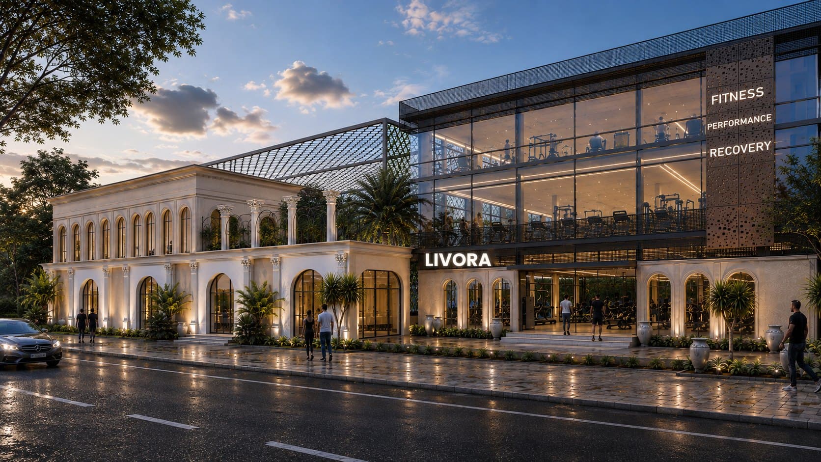 The LIVORA building at dusk: a limestone arcade beside a glazed two-storey training hall, lit warm against a blue evening sky.